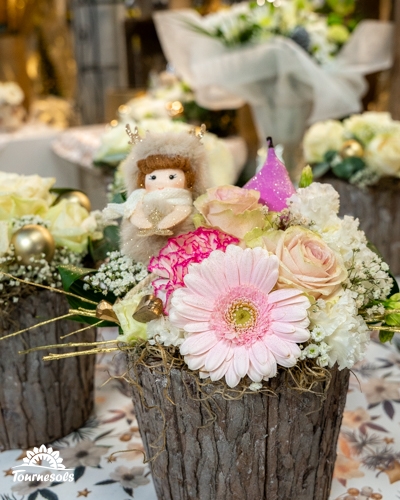 Composition florale de Noël avec fleurs pastelles et figurine d'ange.